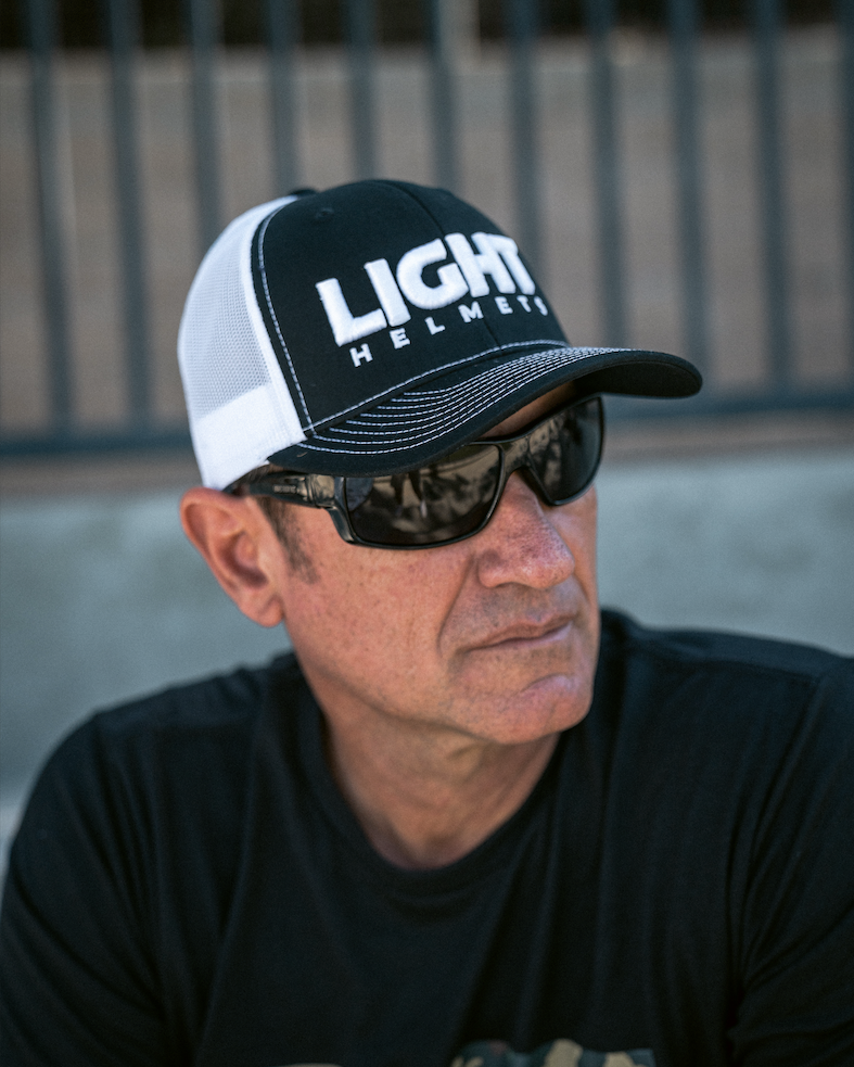 Man wearing a black and white cap with 'LIGHT HELMETS' text and sunglasses.