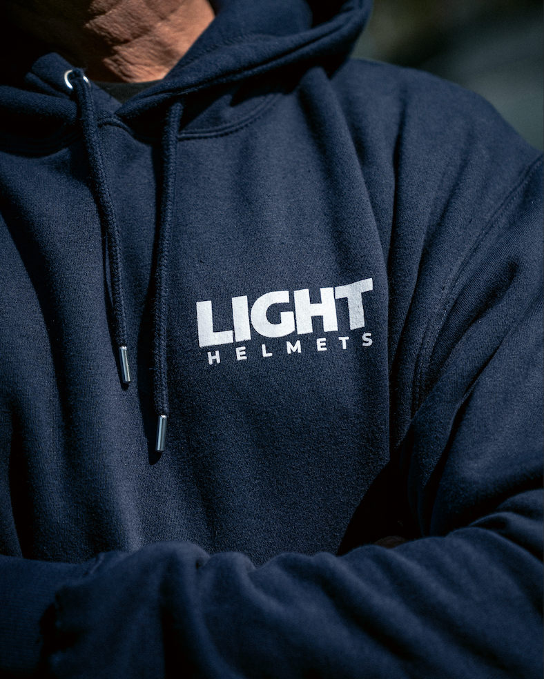 Navy hoodie with 'LIGHT HELMETS' logo on a blurred background