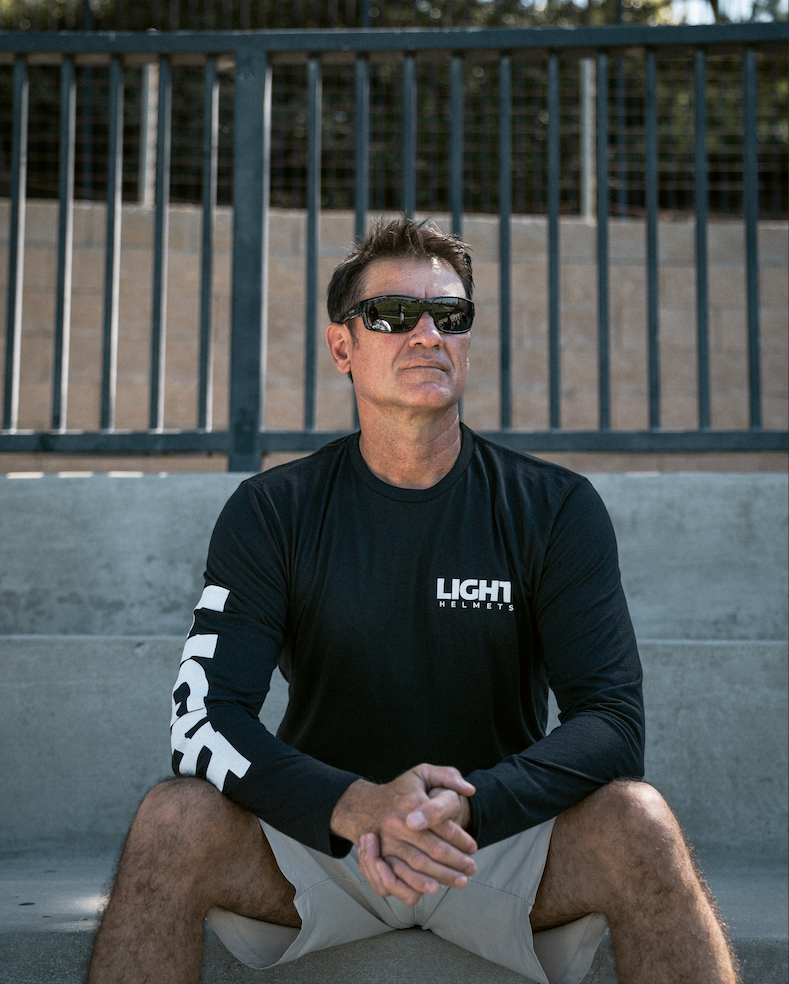 Man wearing a black long-sleeve shirt with 'LIGHT HELMETS' logo sitting on steps.