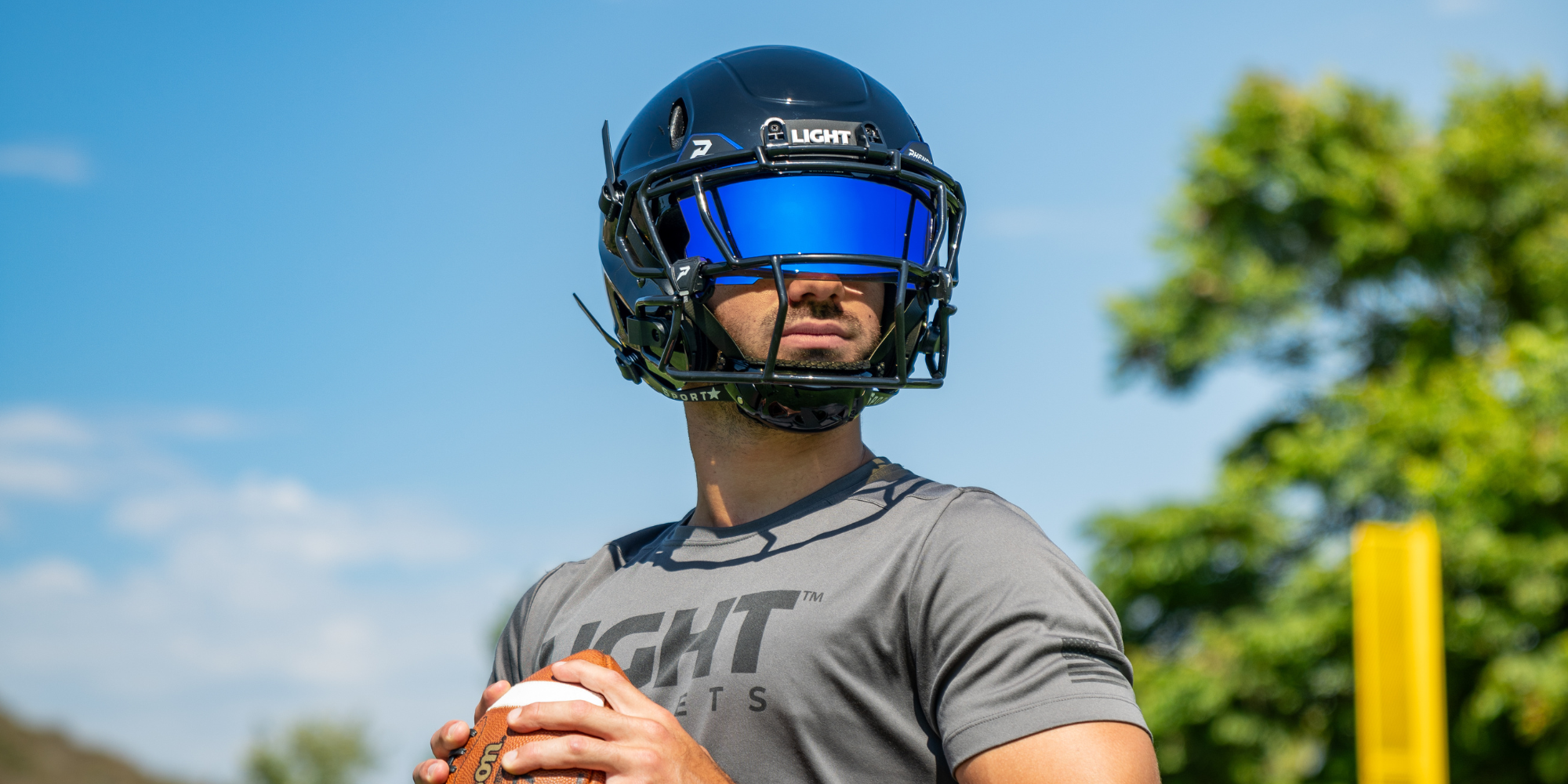 Football player wearing a gloss black LIGHT LS2 football helmet with a Phenom blue tint visor